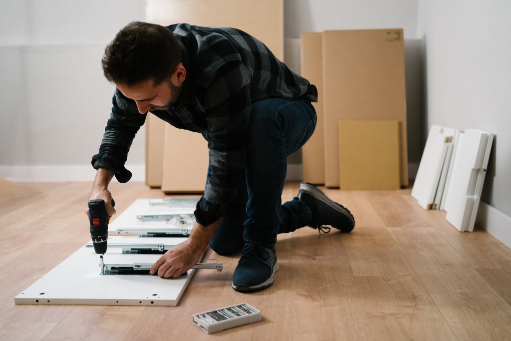 Férfi szekrényt szerel össze akkus csavarhúzóval